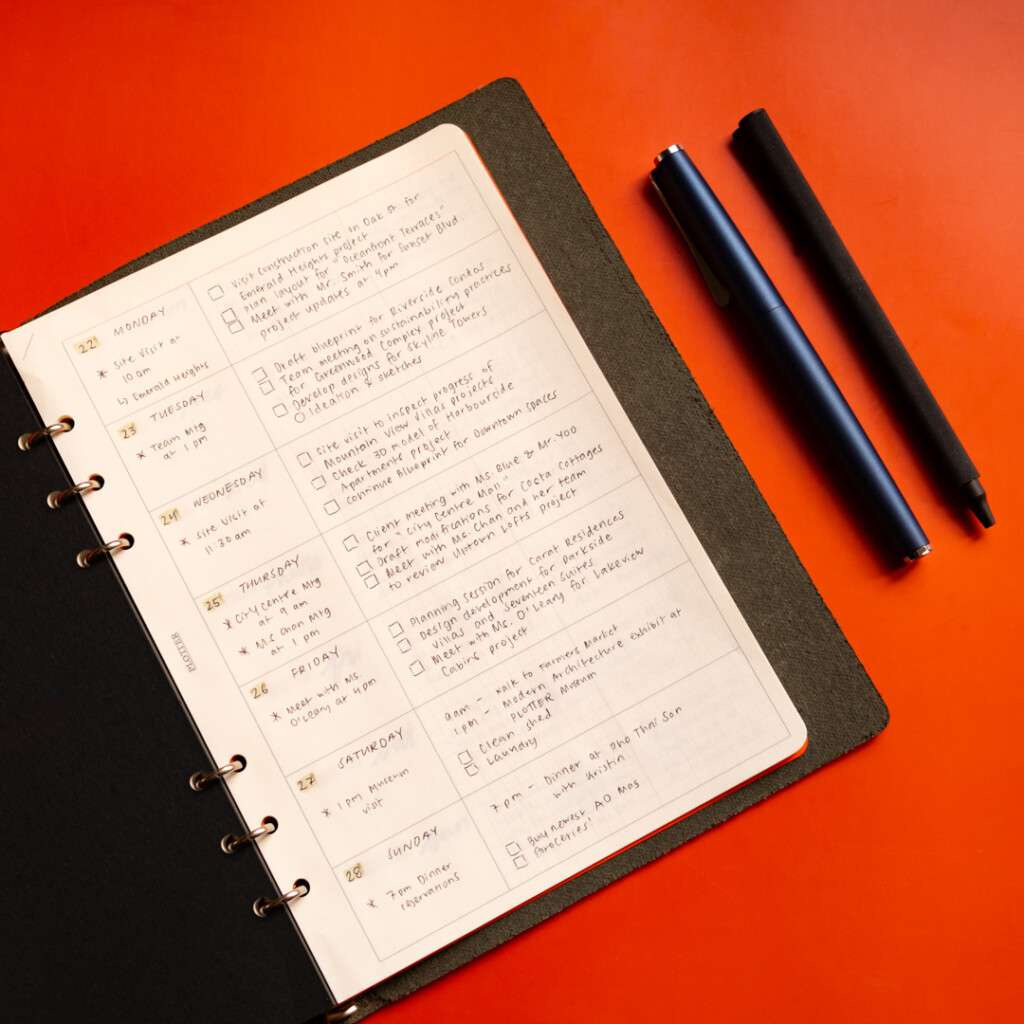 A5 Chart Grid refill used as a weekly schedule in PLOTTER leather binder with pens beside it.
