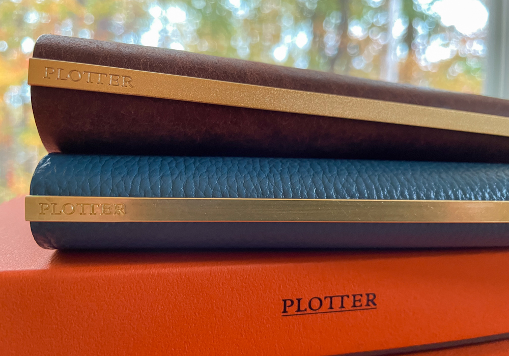 Stack of two PLOTTER leather binders with a gold backplate.