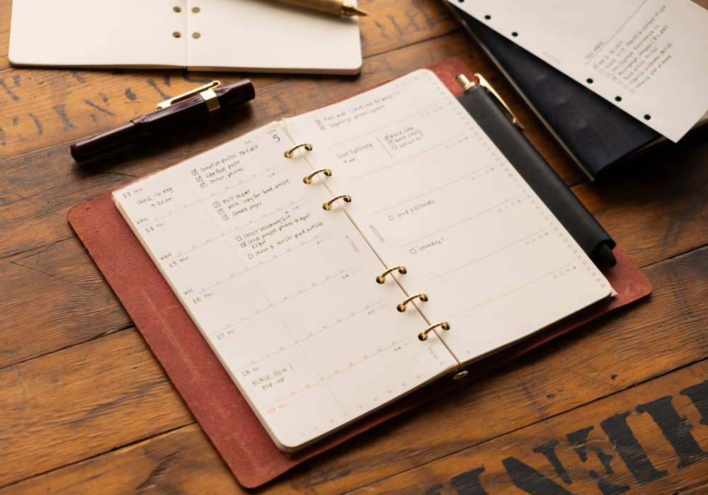 Weekly schedule notes inside a PLOTTER leather binder.