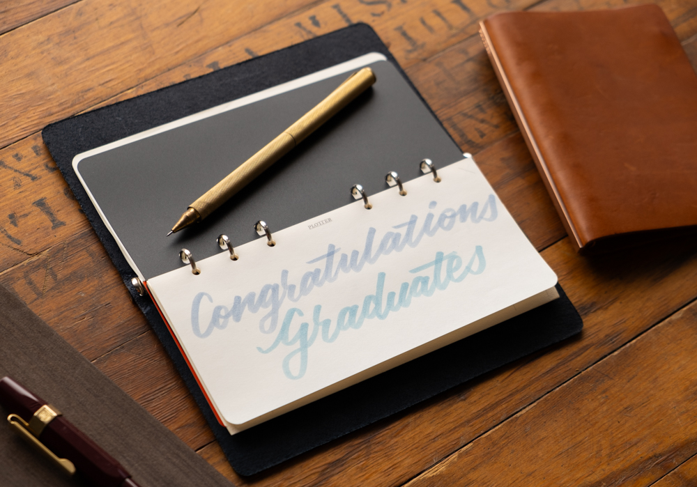 PLOTTER Leather Binder open with text saying "Congratulations Graduates".