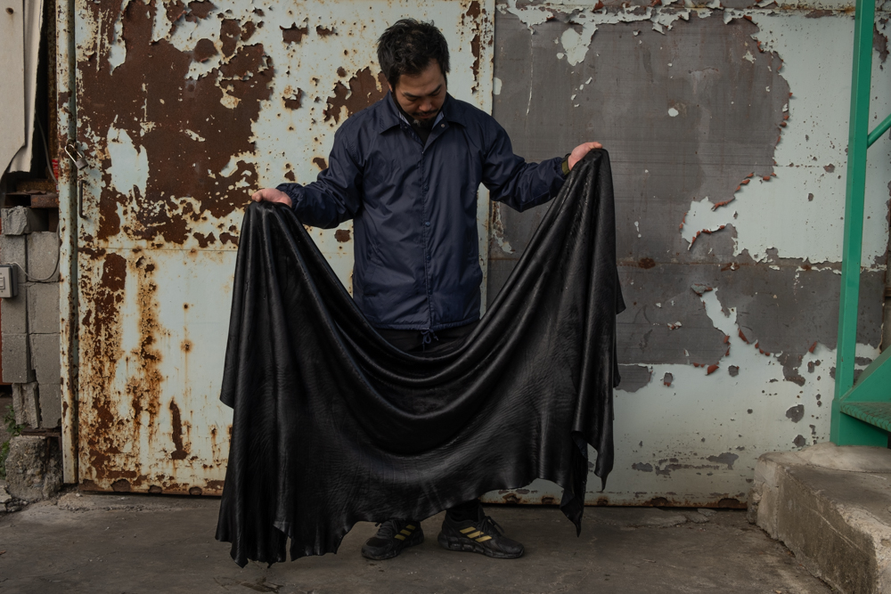 Leather craftsman holding the dyed Shiranami leather. 