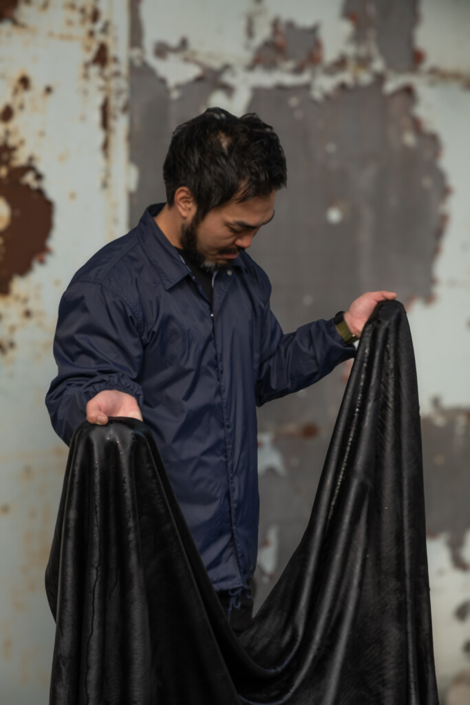 Leather craftsman holding the dyed Shiranami leather. 