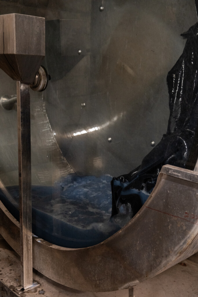 Indigo-dyed leather in a spinning dyeing drum in a blue dye solution. 
