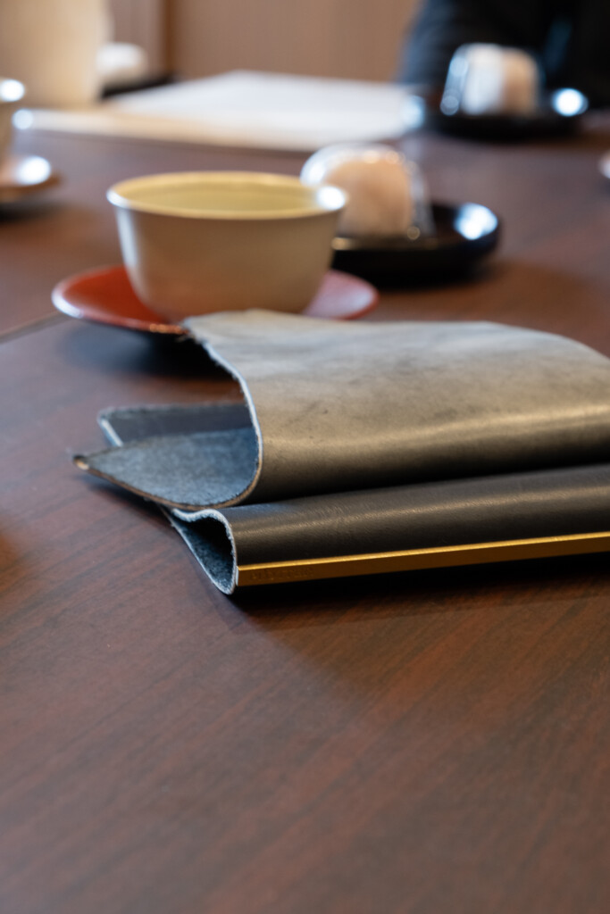 Close-up of the prototype of Shiranami leather that is darker and does not have wax compared to the final version of Shiranami leather that has indigo dye and white wax.