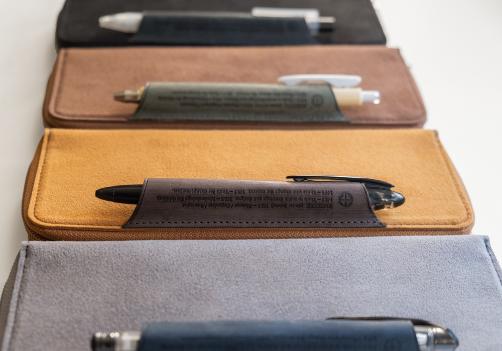 Four PLOTTER Long Zipper Pen Cases in a row, each holding a pen on its exterior pen loop.