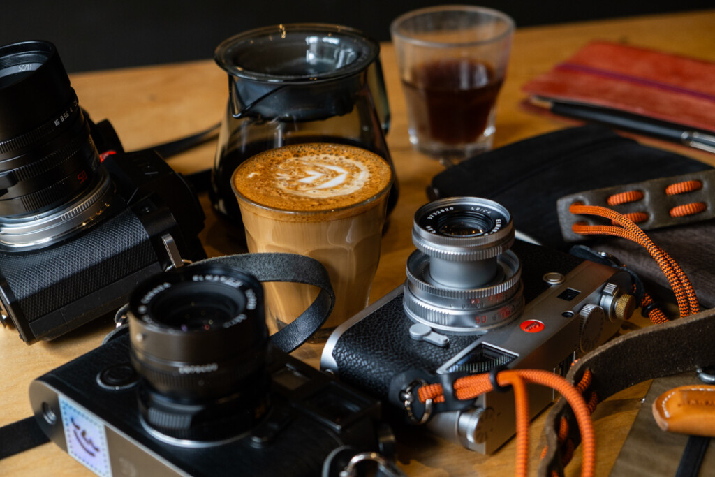 Close-up of cameras with PLOTTER leather binders on wooden table.