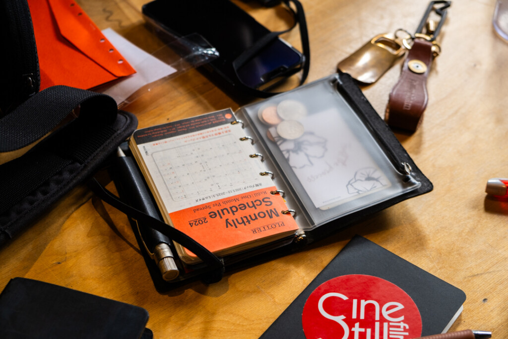 Wooden table with cameras and open PLOTTER leather binders in mini size with coffee cups.