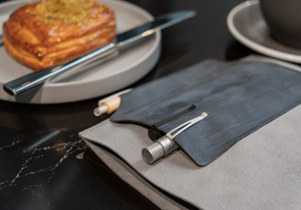 PLOTTER Leather Binder on marble table beside a croissant.