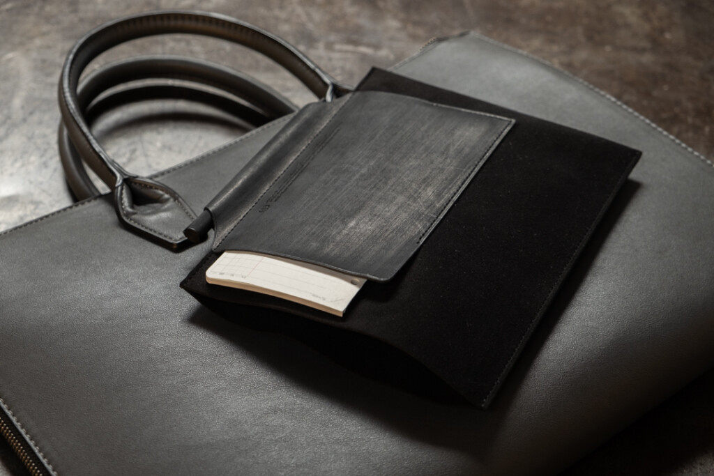 PLOTTER Leather Binder Case Bible Size in black on top of a briefcase on a metal table.