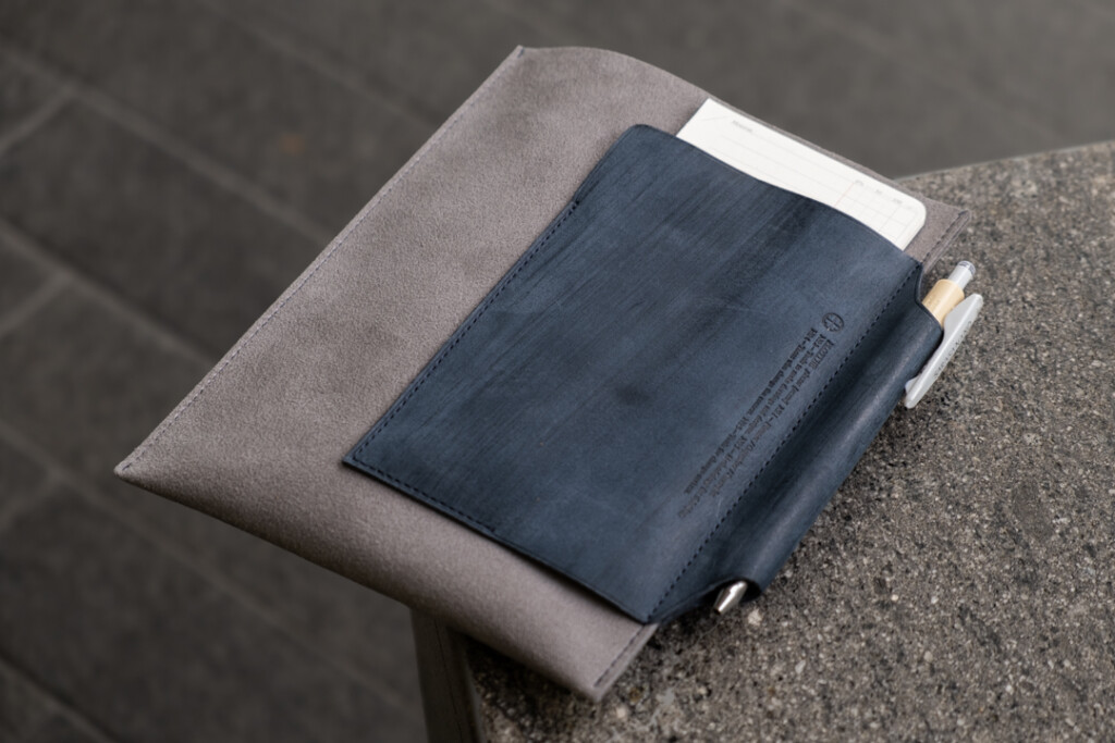 PLOTTER Leather Binder Case in Bible Size in the Grey and Blue color way on the corner of a bench.