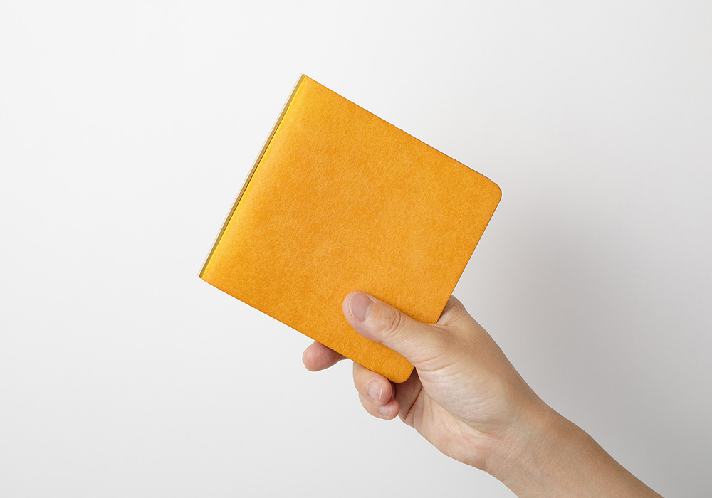 A hand holding a yellow 5-Ring Leather Binder in Mini 5 Square size against a white background.