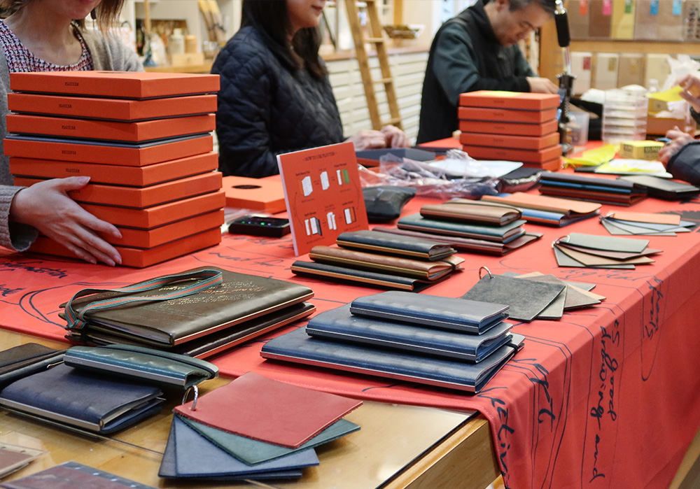 A PLOTTER Pop-up with leather binder and leather samples spread out on the table.