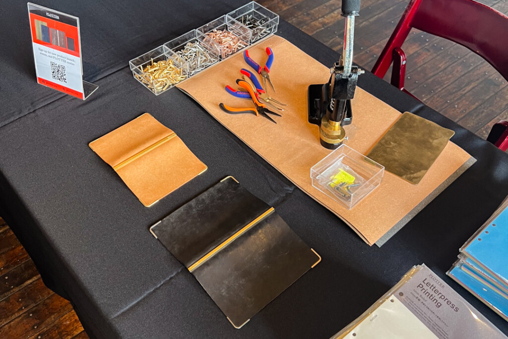 PLOTTER USA corner hardware machine beside other tools and PLOTTER Leather Binders on a table.