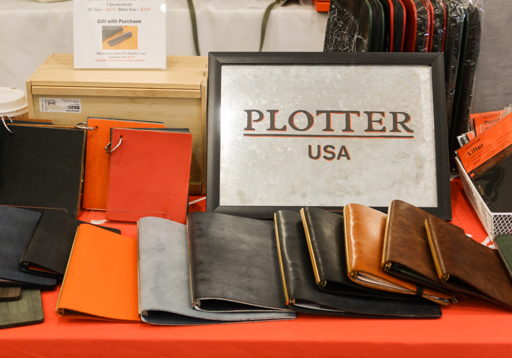 PLOTTER leather binder samples laid out on a table with a sign that says PLOTTER USA.