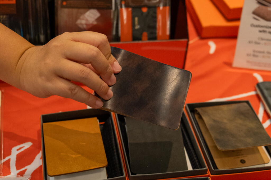 A person holding a PLOTTER 3-Ring Leather Binders in front ofother PLOTTER 3-Ring Leather Binders in various colors.