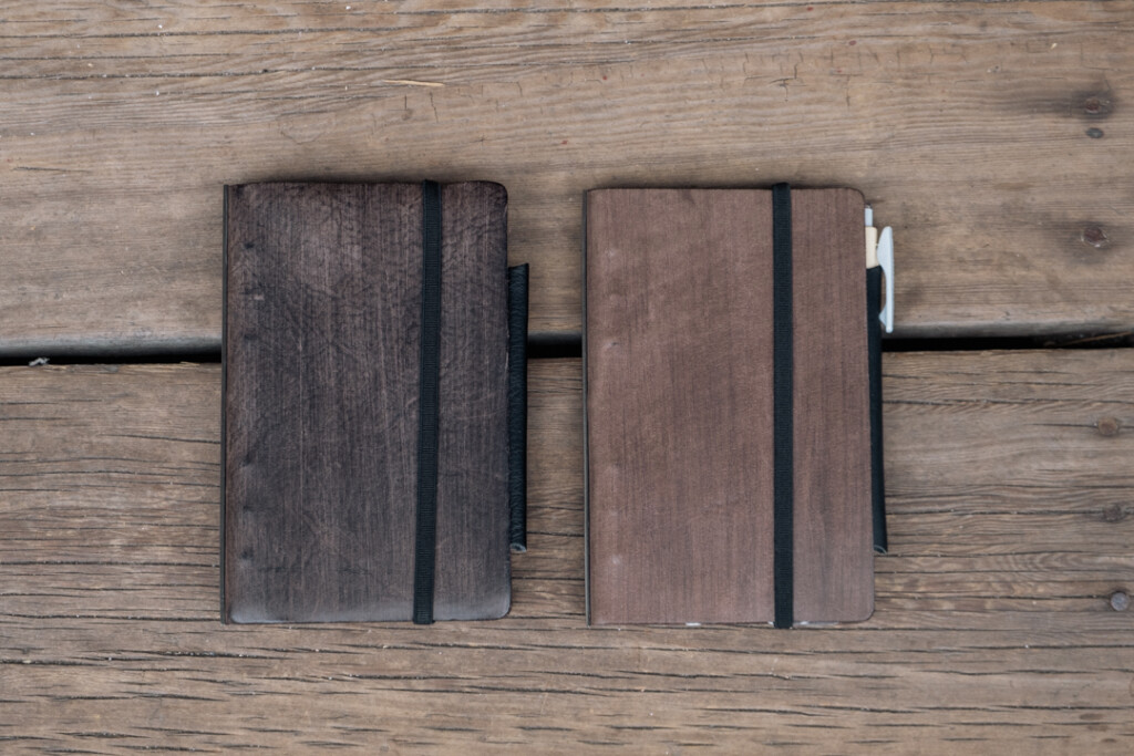 Two Gray PLOTTER Leather Binders in Horse Hair II Leather in Bible Size side-by-side on wooden table.