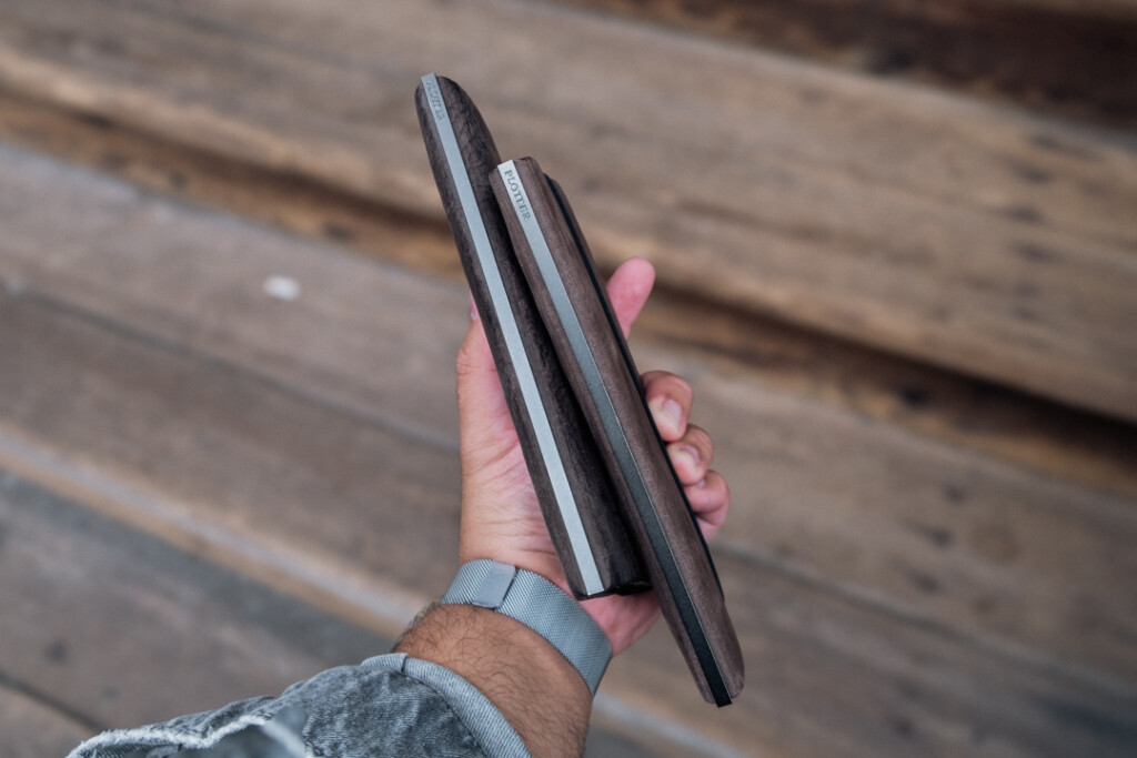 Man holding two Gray PLOTTER Leather Binders in Horse Hair II Leather in Bible Size in front of wooden stairs.