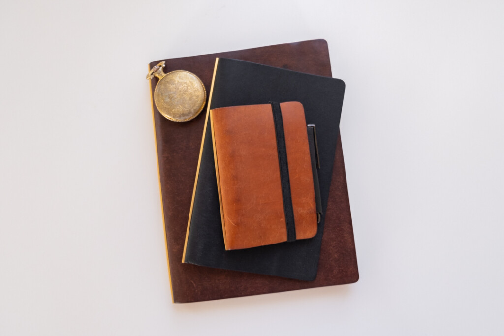 A stack of PLOTTER Leather Binders with a vintage stop watch on one of the binders.