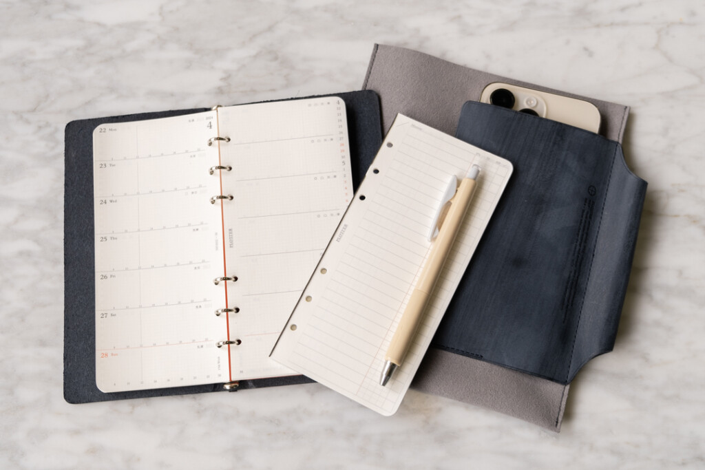 PLOTTER Narrow Size open to a weekly schedule beside a blank refill memo pad and Leather Binder Case in grey and blue.