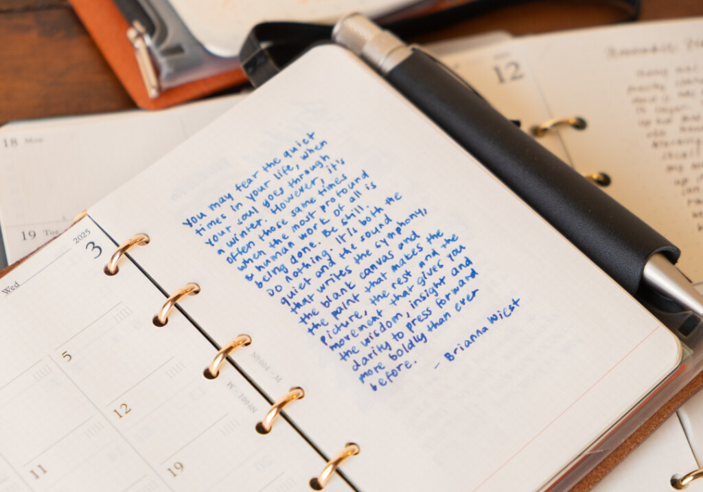 Close-up view of a PLOTTER Mini Size Leather Binder with writing on the page with blue ink.