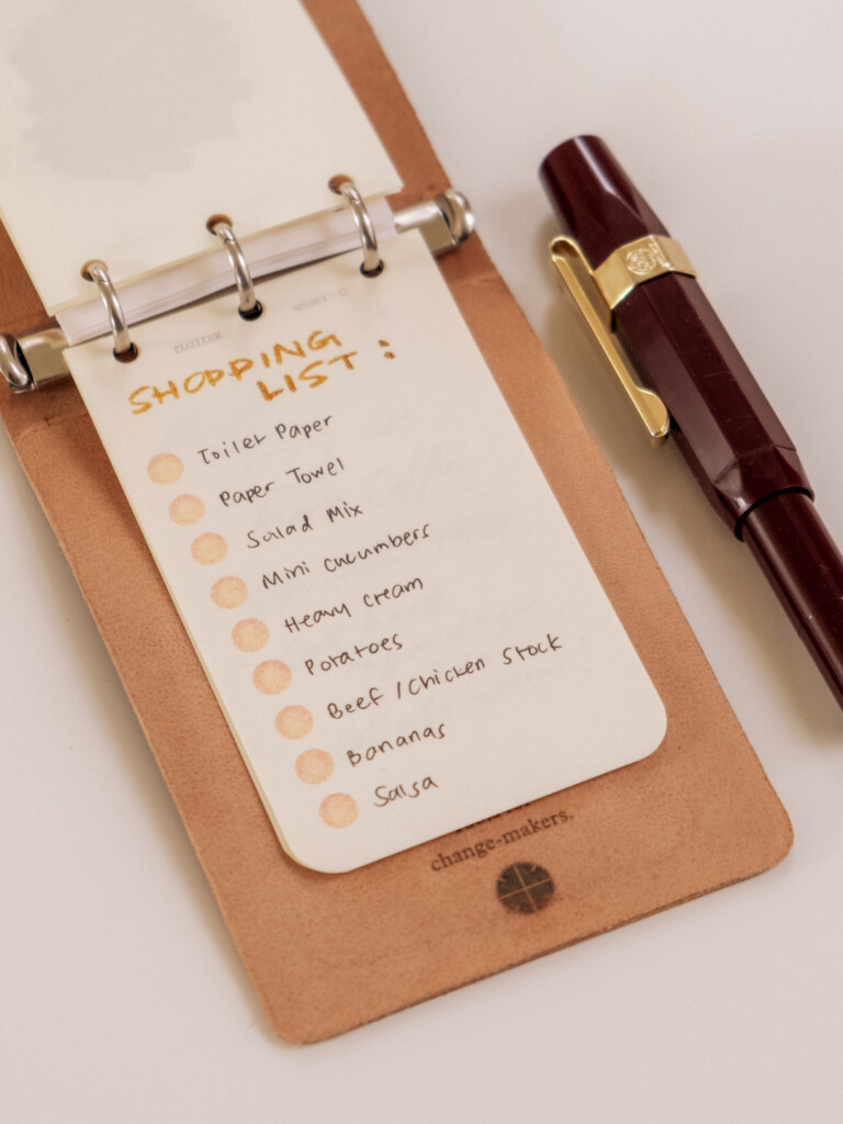 PLOTTER 3-Ring Leather Binder open to a shopping list of groceries.