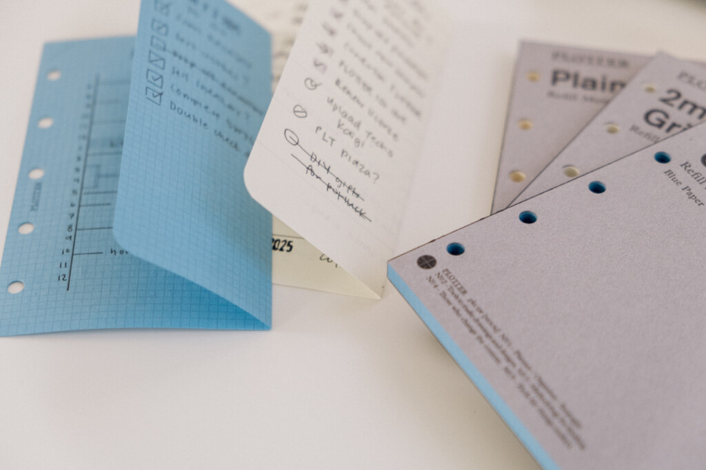 Mini 5 Square refills in Blue Paper and Plain Paper folded in half to show that they fit into a PLOTTER Mini 5 Leather Binder.