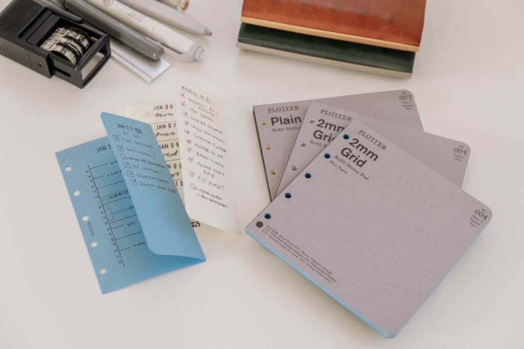 Mini 5 Square refills in Blue Paper and Plain Paper folded in half to show that they fit into a PLOTTER Mini 5 Leather Binder.