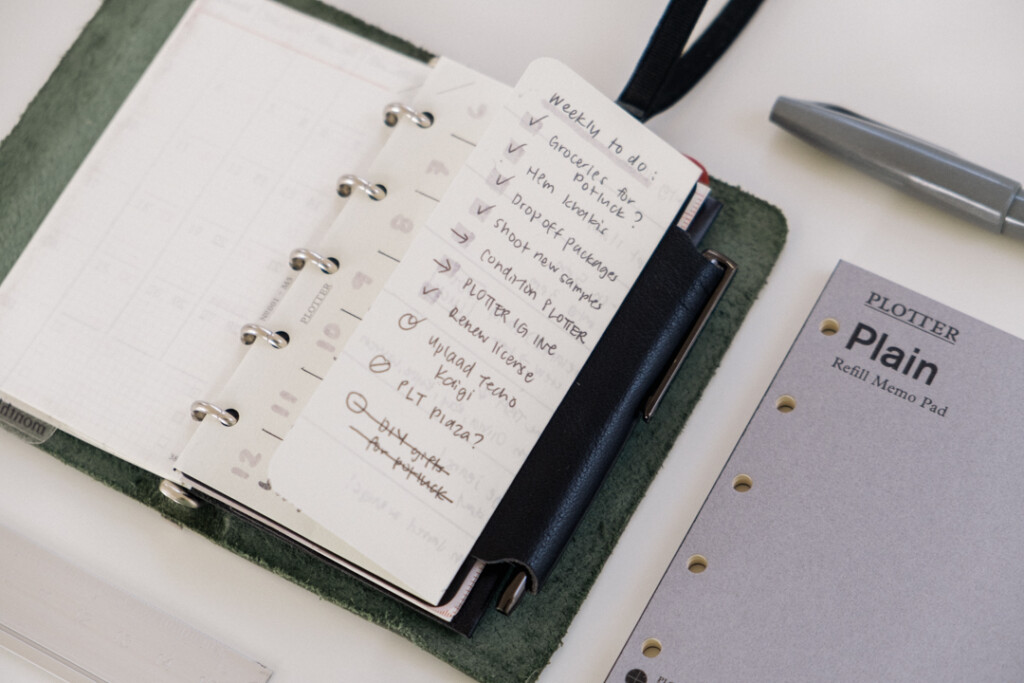 Mini 5 Square refills in Plain Paper unfolded to show that it extends past the PLOTTER Mini 5 Leather Binder so that you can write your full week's schedule on it beside the Refill Memo Pad the paper came from.