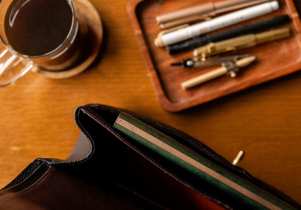 A PLOTTER Leather Binder inside a black leather hand bag.