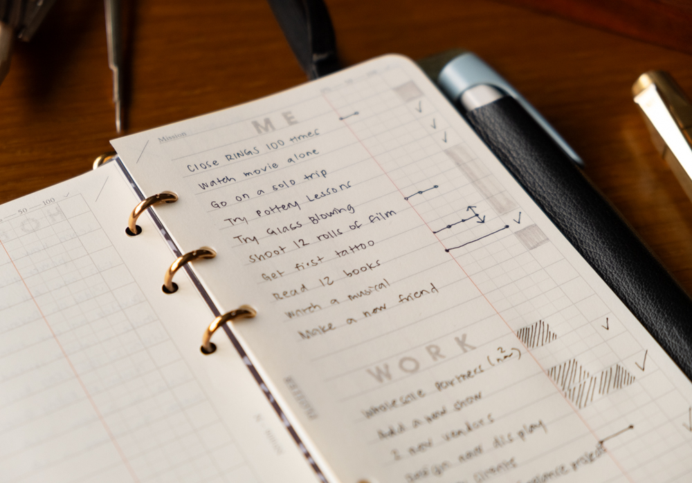 A close up of a PLOTTER Narrow Size Leather Binder open to a List of new year's work and personal goals.