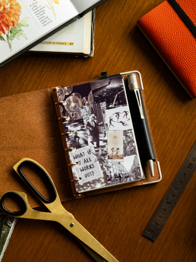 A PLOTTER Mini Size Leather Binder open to a a vision board of images that relate to the owner's goals.