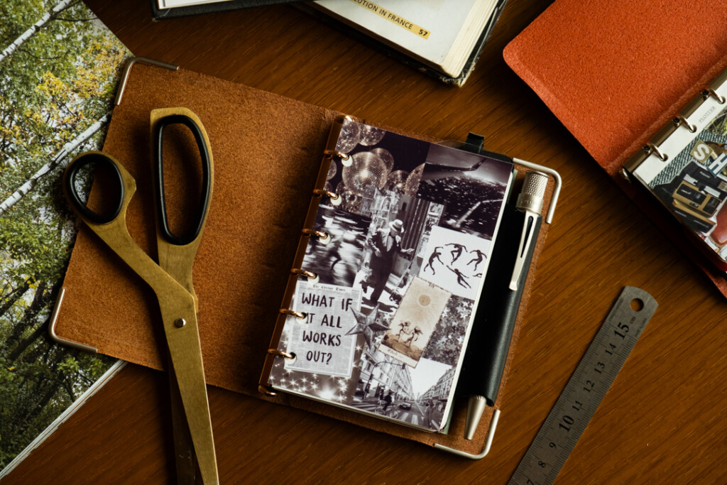 A PLOTTER Mini Size Leather Binder open to a a vision board of images that relate to the owner's goals.