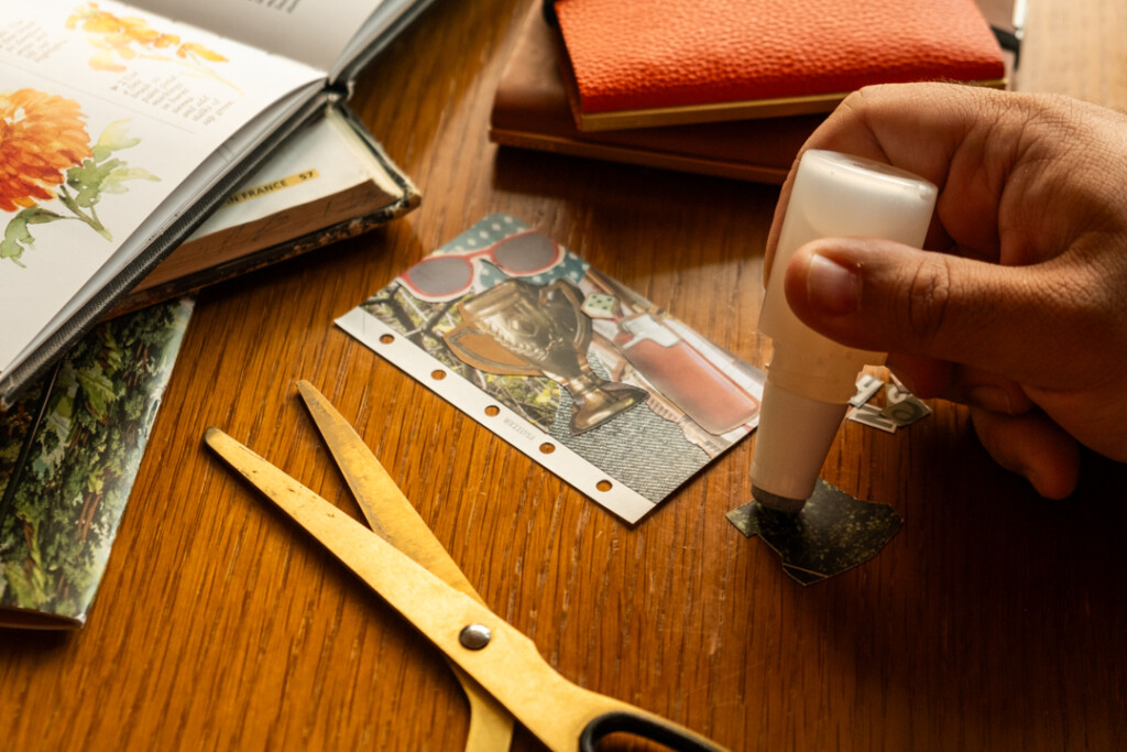 A person completing a vision board that fits into a PLOTTER Mini 5 Size beside PLOTTER Leather Binders and collaging materials.