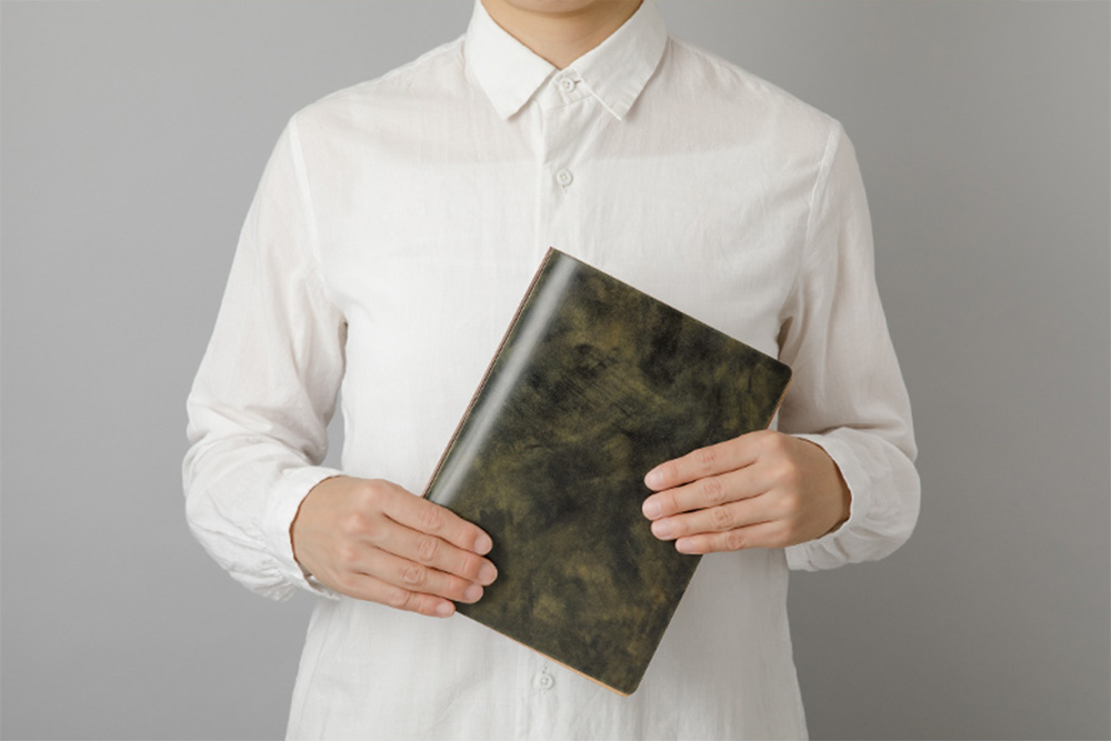 Man holding a green Unevenly-dyed Cordovan Leather Binder in A5 Size.