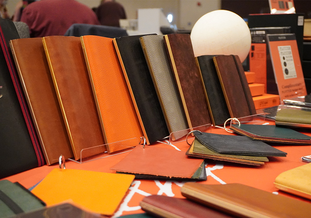 A row of PLOTTER leather binders displayed on a table at CA Pen Show 2023.