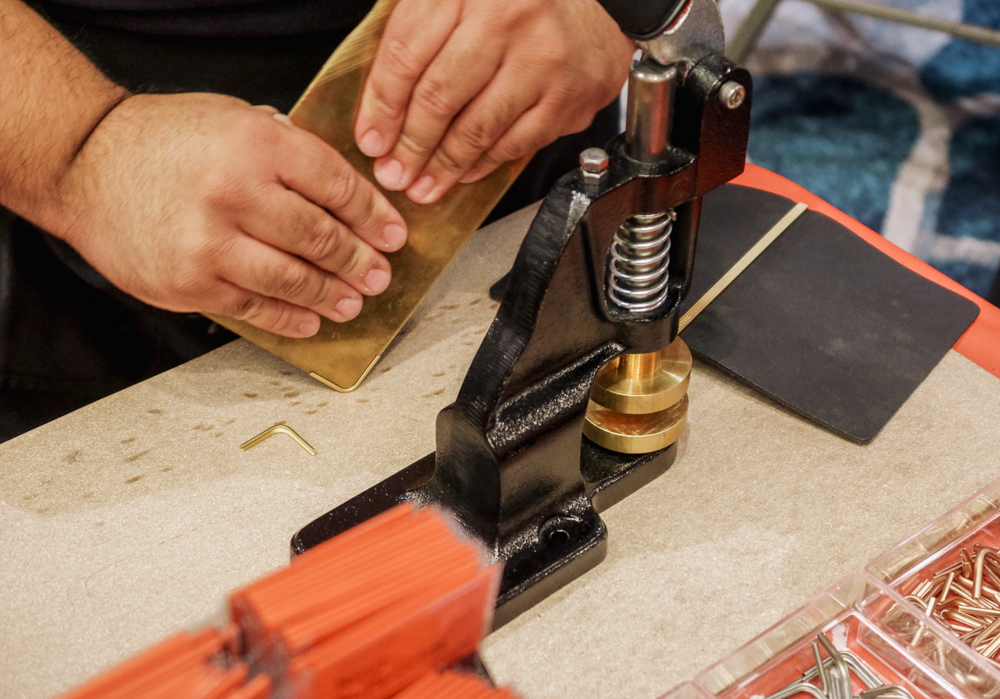 Craftsman preparing the PLOTTER Corner Hardware attachment at the PLOTTER USA table at the California Pen Show.