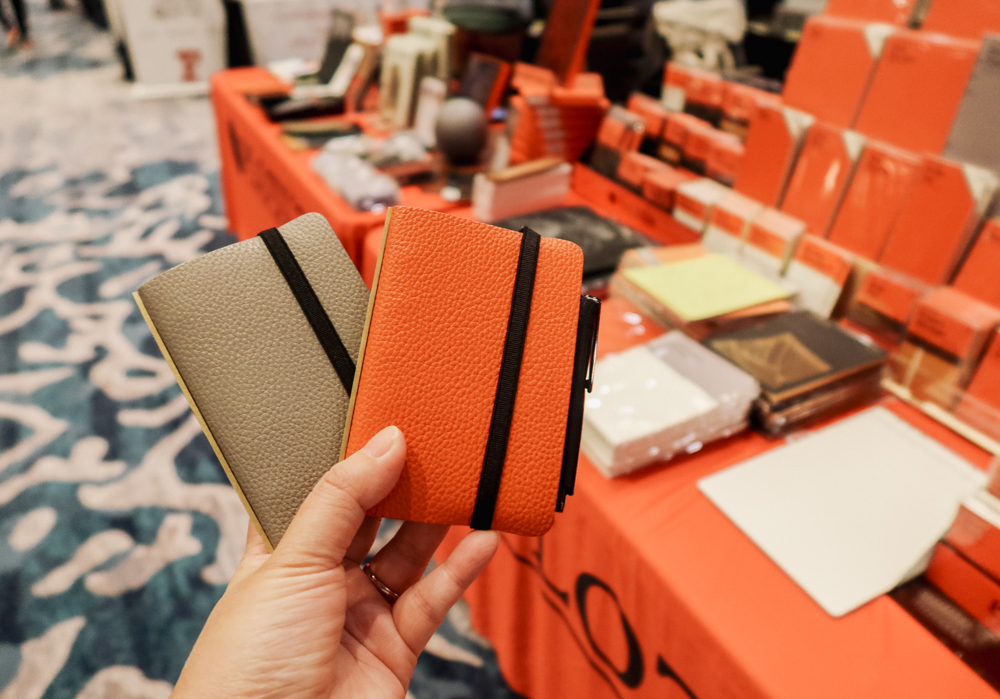 Person holding two PLOTTER Mini 5s in Orange and Gray Shrink Leather.