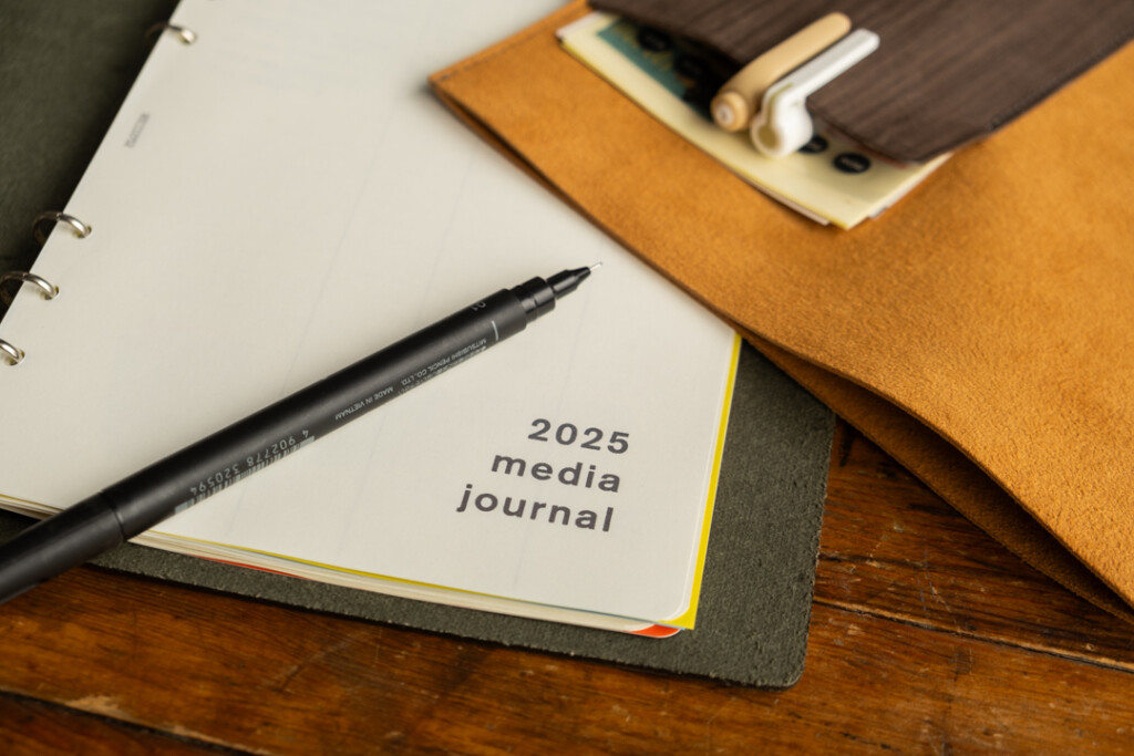 PLOTTER Leather Binder A5 Size open to a media journal section beside a Leather Binder Case in Yellow and Gray.