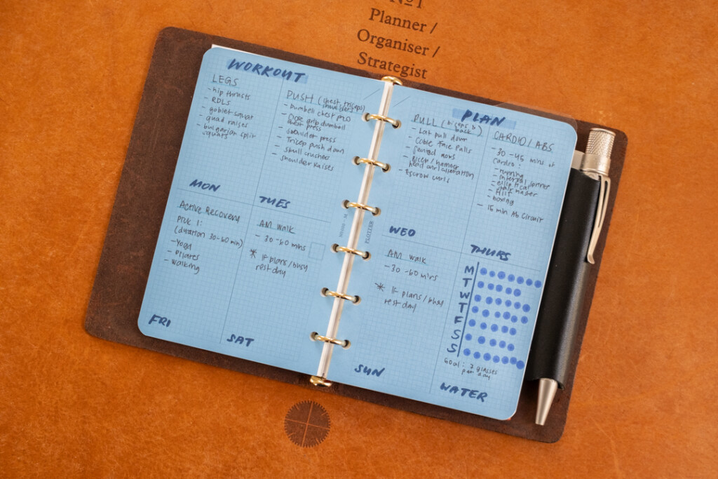A PLOTTER Mini Size open to a spread with a workout routine and water intake tracker.