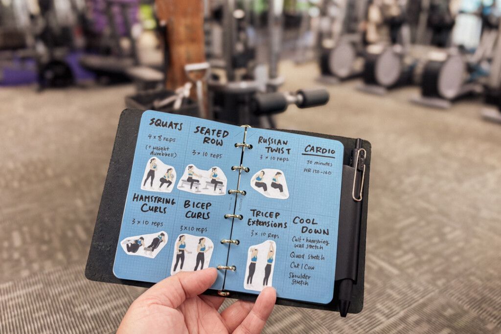 Person holding a PLOTTER Mini Size open to a spread with a workout routine with images of the exercises.