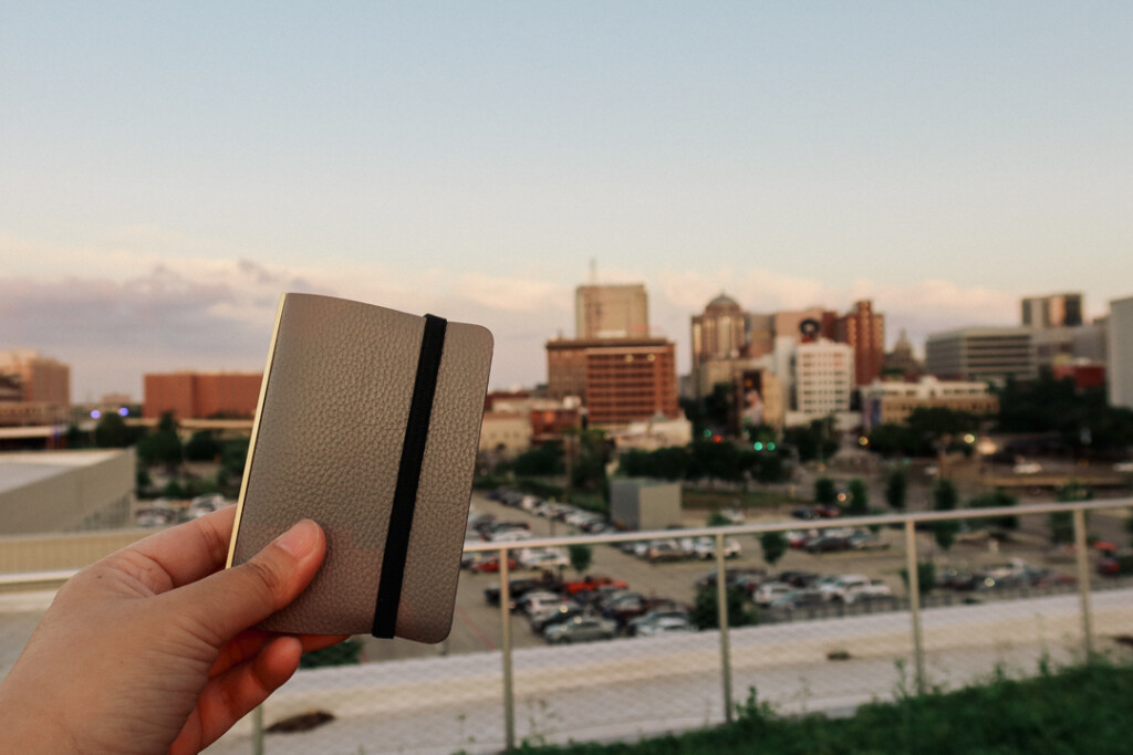 Person holding a PLOTTER Mini 5 Leather Binder in front of the Houston, Texas skyline.