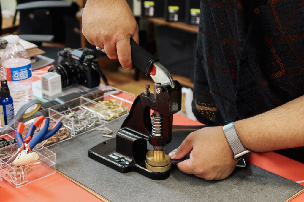 PLOTTER corner hardware customization machine being used to add corners to a black PLOTTER Leather Binder.