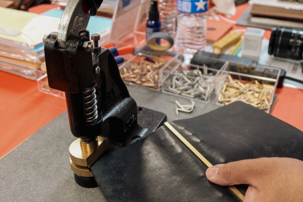 PLOTTER corner hardware customization machine being used to add corners to a black PLOTTER Leather Binder.