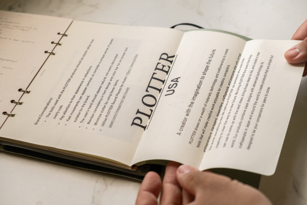 A person folding out a printed sheet of A4 PLOTTER Paper that was folded to fit into an A5 PLOTTER Leather Binder.